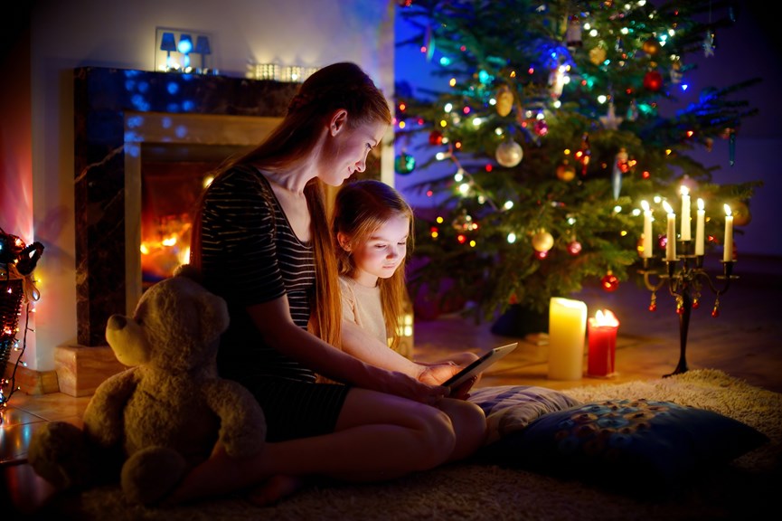 Μαμά και παιδί διαβάζουν παραμύθι με φόντο το χριστουγεννιάτικο δέντρο