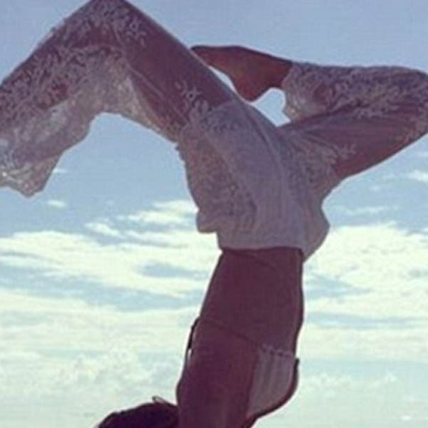 Κάνει yoga στην παραλία με λευκή αραχνοϋφαντη παντελόνα